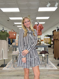 The Blair dress - Black-and-cream houndstooth dress with a tie-neck detail, long sleeves, and a flowy tiered silhouette.