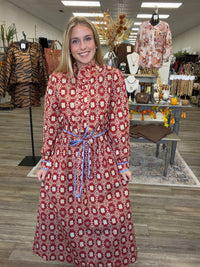 Crimson Charm Dress – A bold crimson midi dress featuring a cream floral-inspired print, feminine ruffle detailing, a flattering tie waist, and pops of blue trim