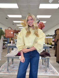 The Eloise blouse - a butter-yellow button-front blouse featuring an oversized collar, dramatic balloon sleeves, and gathered ruffle cuffs.