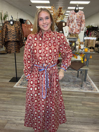 Crimson Charm Dress – A bold crimson midi dress featuring a cream floral-inspired print, feminine ruffle detailing, a flattering tie waist, and pops of blue trim