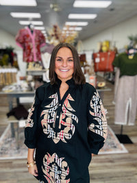 The Windsor Bloom Dress -  black long-sleeve tunic dress with beige, red, and plaid-inspired ornate floral patterns and a ruffled neckline.