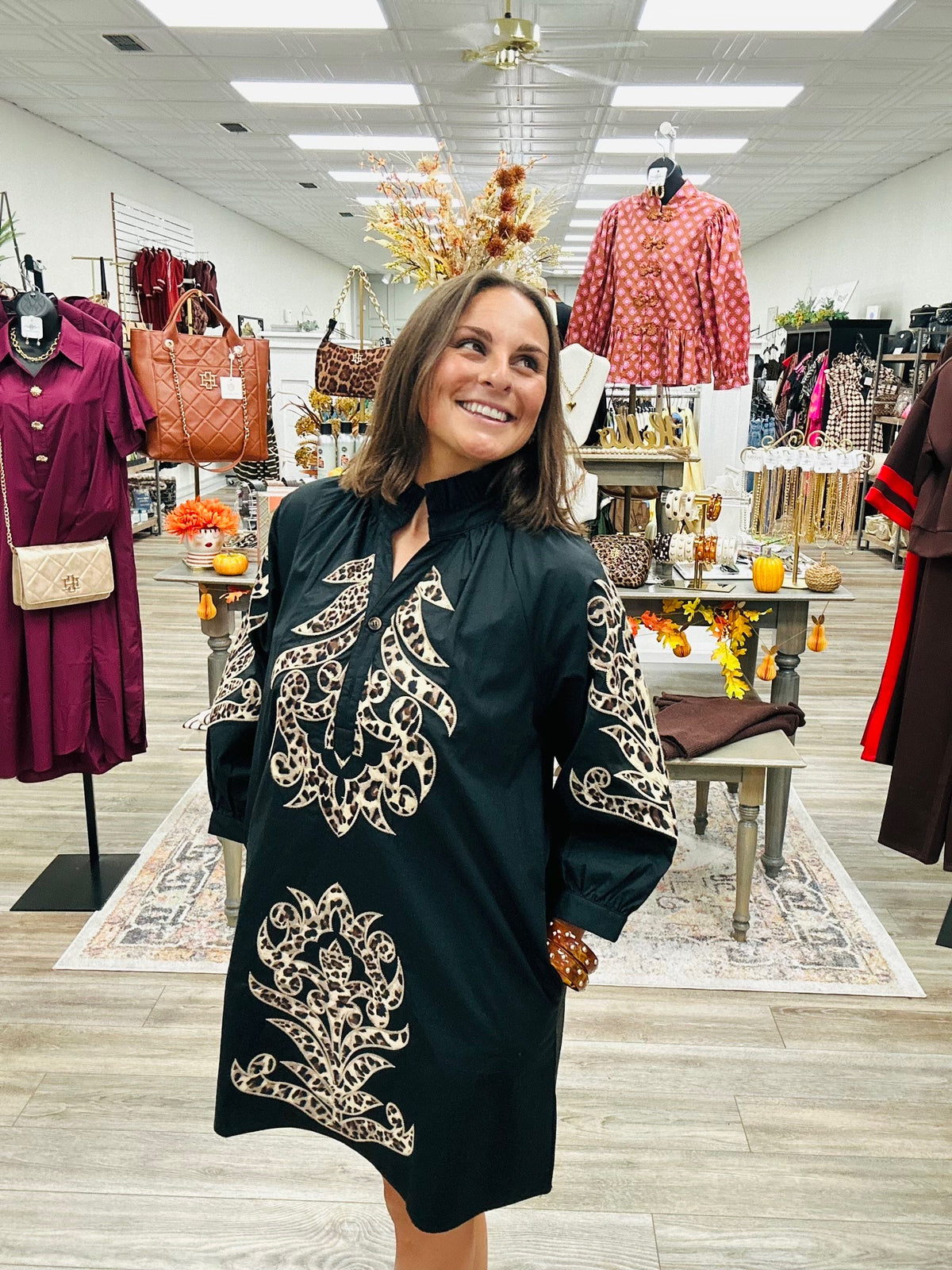 The Savannah Luxe Leopard Embroidered Tunic features a classic black fabric with leopard- inspired embroidered detailing. Ruffled mock neckline and three- quarter puff sleeves.