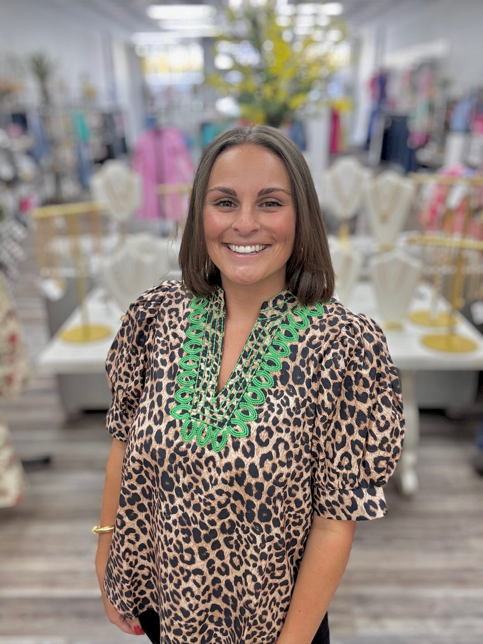 The Evangeline blouse - leopard print blouse featuring a V-neckline with bright green embroidery trim, puff sleeves, and a flowy silhouette. Entro style#T31886