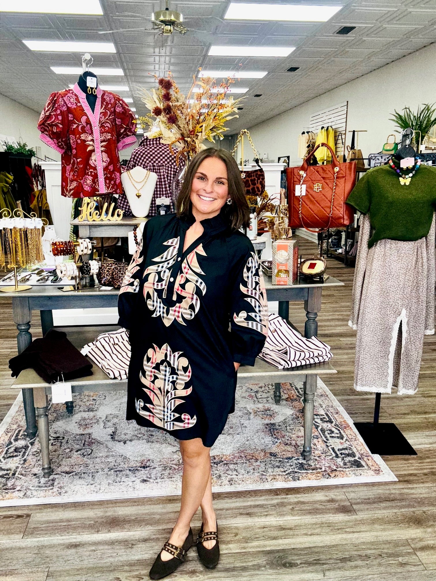 The Windsor Bloom Dress -  black long-sleeve tunic dress with beige, red, and plaid-inspired ornate floral patterns and a ruffled neckline.