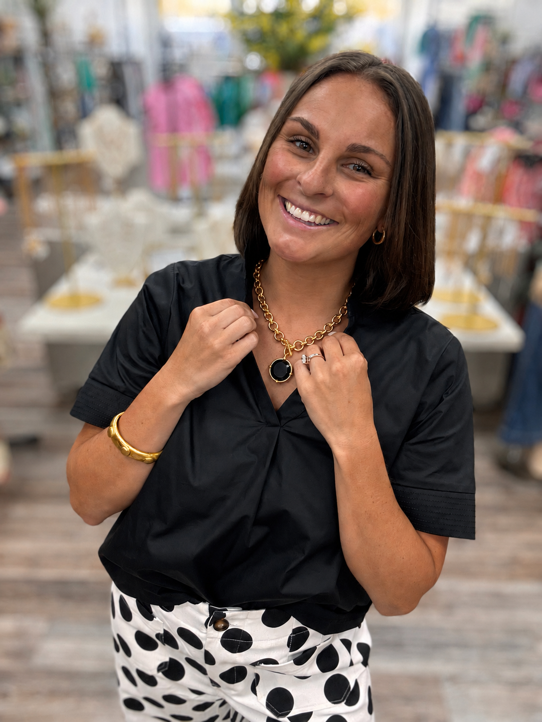 The Scarlett blouse - a black blouse featuring a pleated stand collar, short sleeves with stitched cuff details.