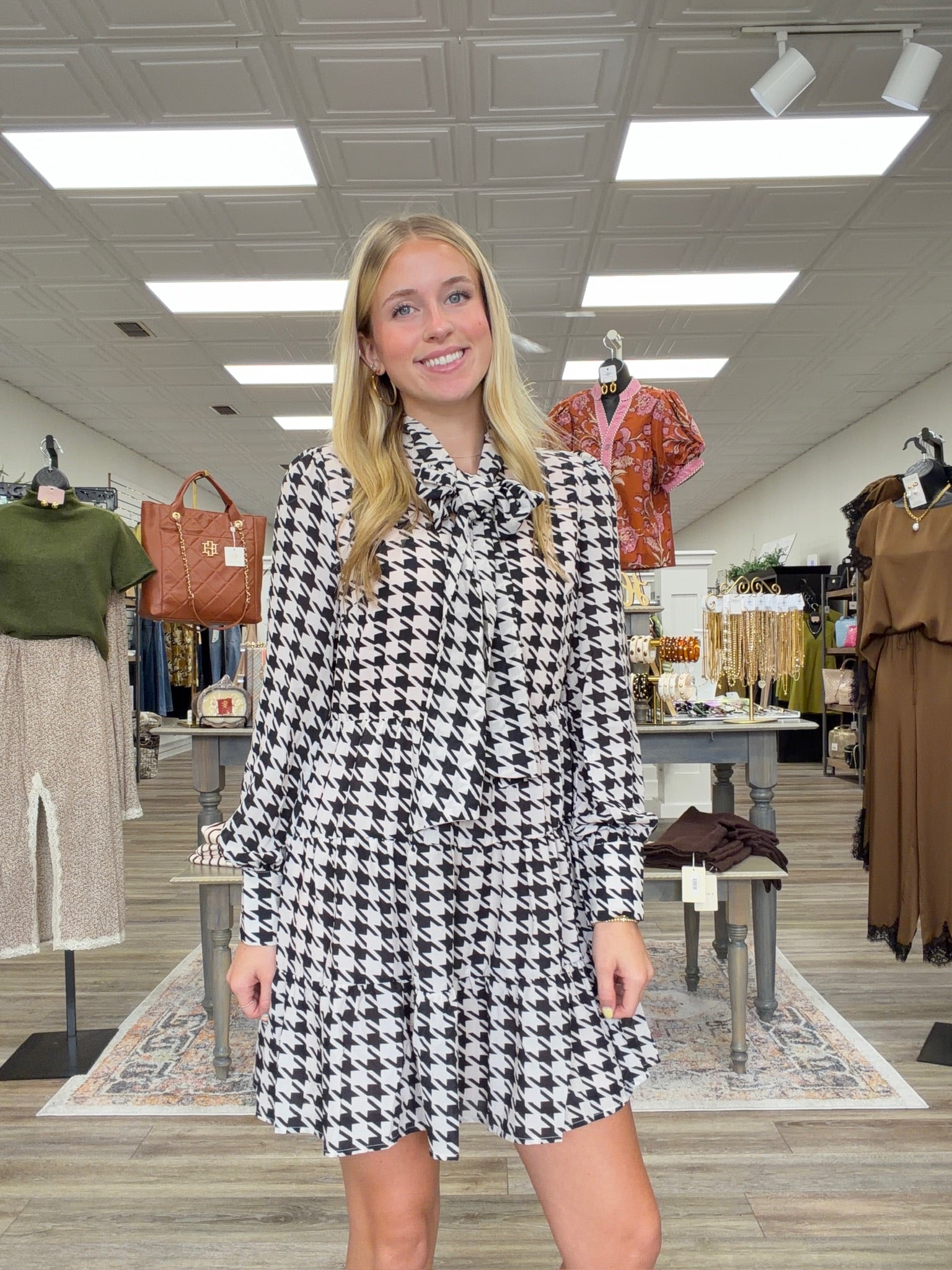 The Blair dress - Black-and-cream houndstooth dress with a tie-neck detail, long sleeves, and a flowy tiered silhouette.
