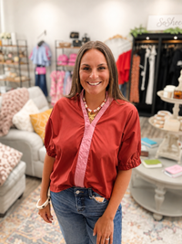 The Sienna top - rust colored top with pink contrast trim, a split neckline, and puff sleeves. Entro
