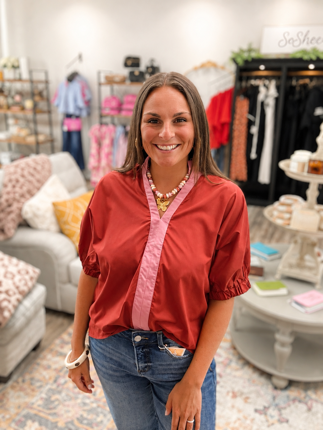 The Sienna top - rust colored top with pink contrast trim, a split neckline, and puff sleeves. Entro